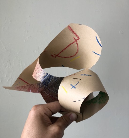 A hand holding a folded paper sculpture