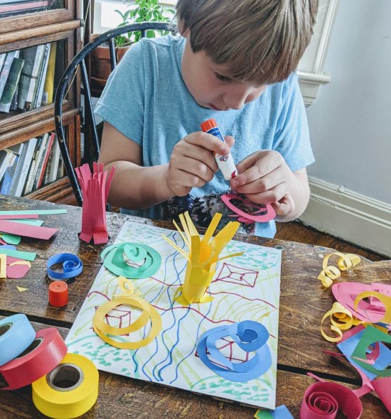 A boy gluing paper strips to a larger paper