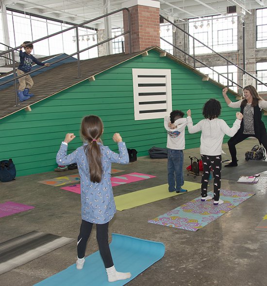 A woman leading a group of kids in yoga poses