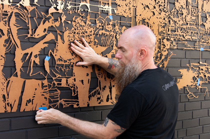 July 3: Artist Logan Hicks begins taping up his custom stencils for the first layer of his mural, Walking Back Time