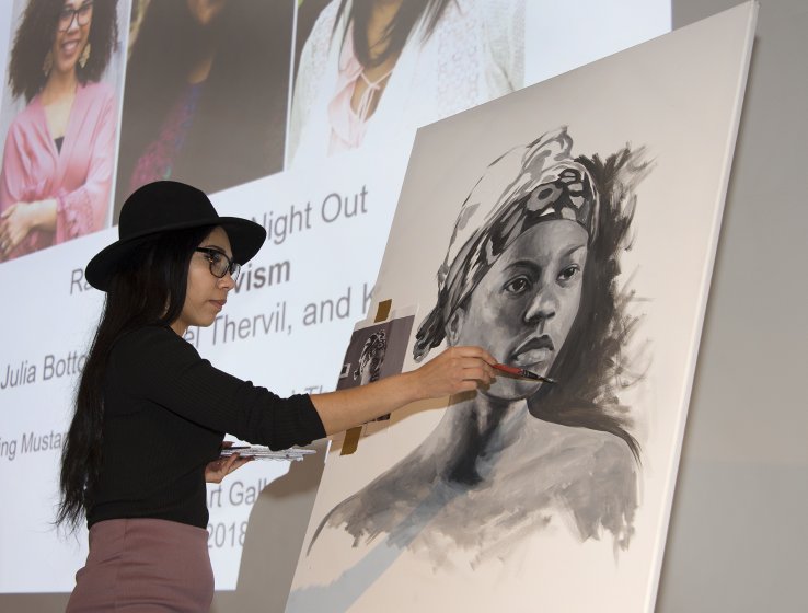 Julia Bottoms draws a portrait on an easel on stage in the Auditorium