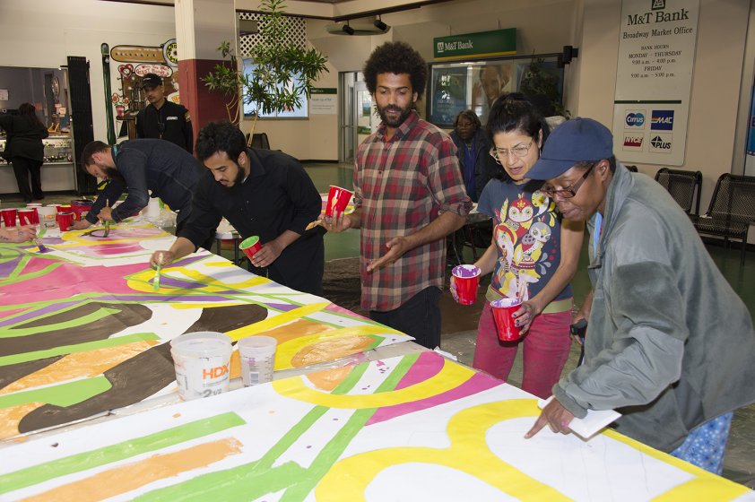 Community members join artists Keir Johnston and Ernel Martinez in painting the mural at Broadway Market.
